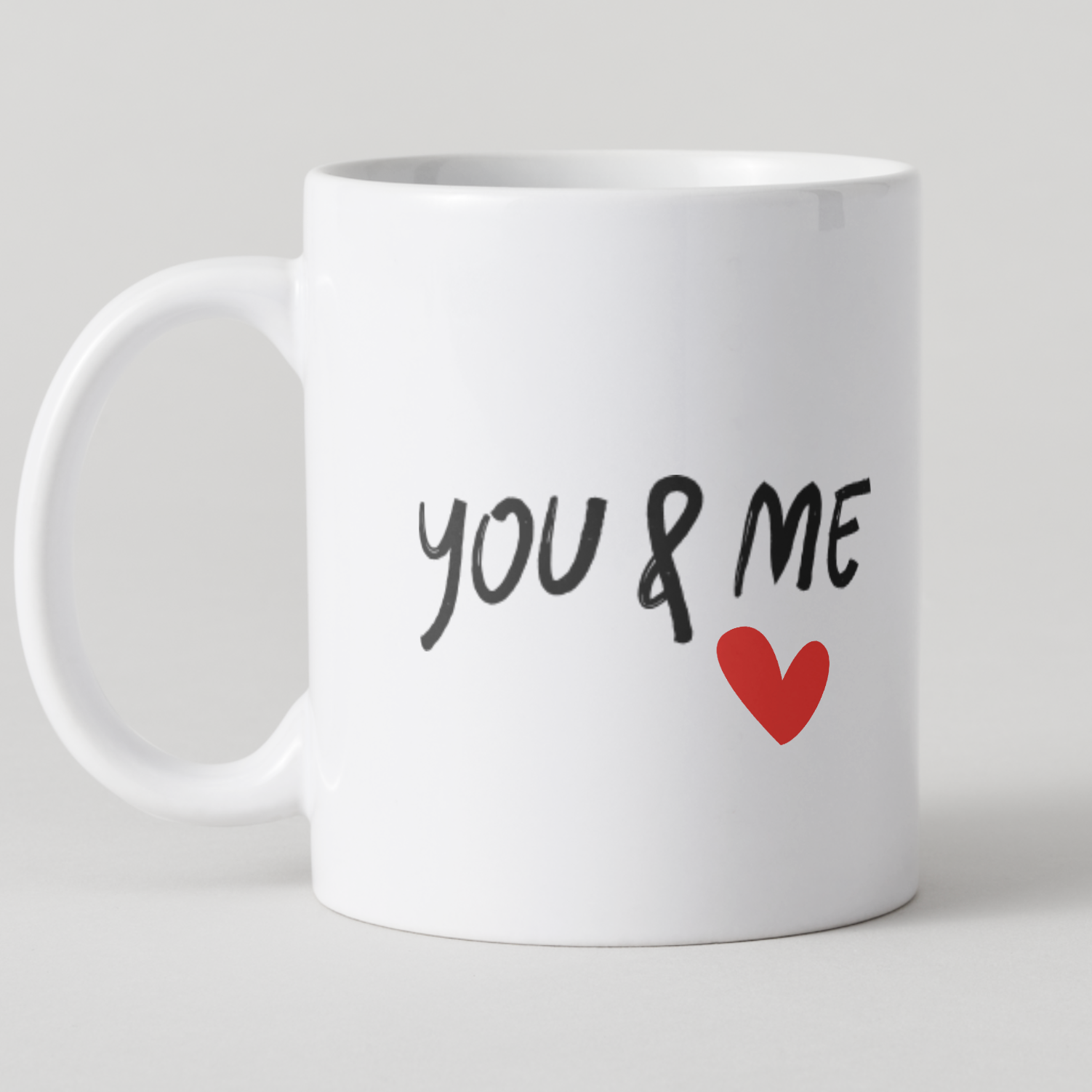 White mug with 'YOU & ME' and a heart on a light gray background